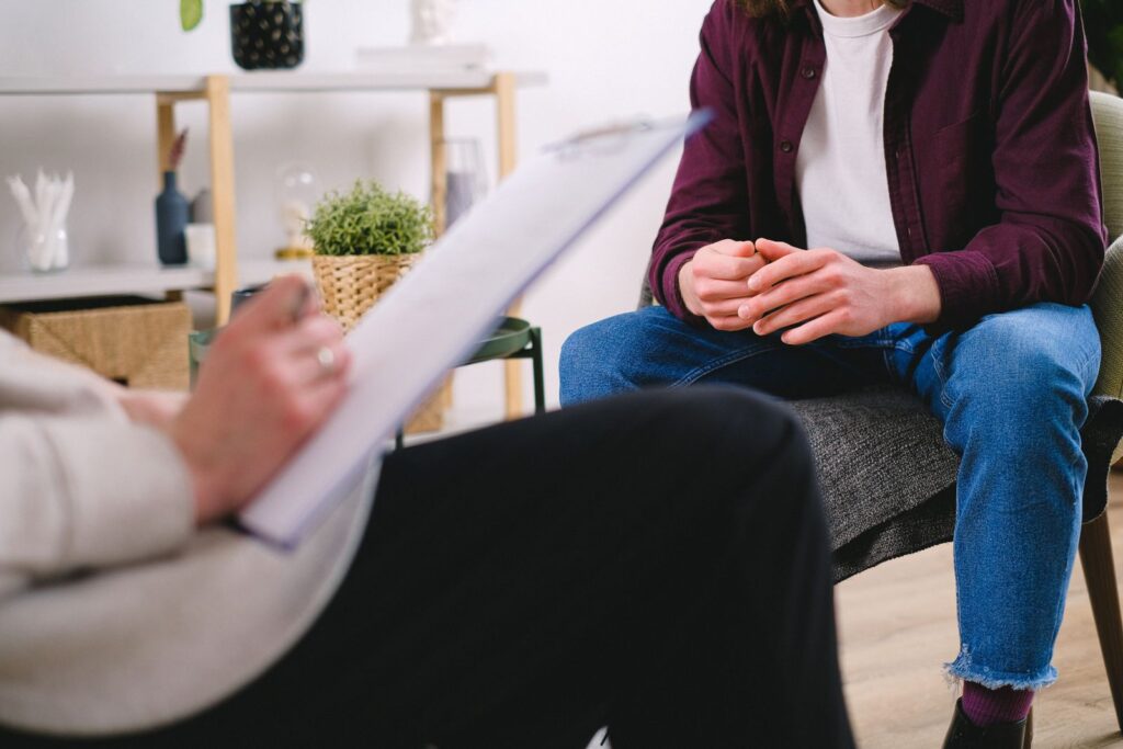 A therapist taking notes while talking with a client in a calm office